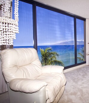 Enjoy the ocean and mountain views from this room's large window, where a comfortable armchair invites relaxation.