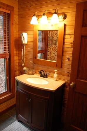 A wooden bathroom with a sink, vanity, and a mirror. - Dreamcatcher-Harvest Moon Cottages (Rockbridge)