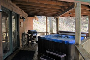 Een houten terras met een jacuzzi, een barbecue en een overdekte entree.