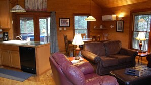 A cozy cabin interior with a kitchen, dining area, and seating space. - Dreamcatcher-Harvest Moon Cottages (Rockbridge)