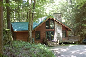 Een chalet met een stenen schoorsteen, houten buitenkant en een veranda.