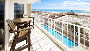 Un balcon avec vue sur une plage et une piscine.