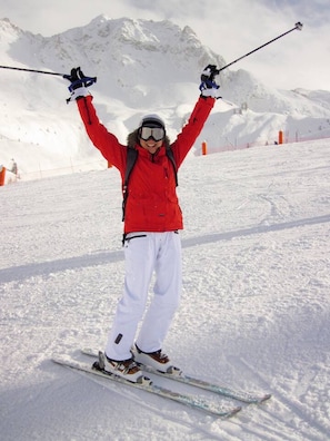 A person skiing on a snowy slope with mountains in the background.