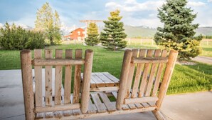 A wooden bench with a backrest and armrests, placed on a concrete surface. - Gorgeous Saddlehorn Cabin - Amazing Teton Views (Driggs)