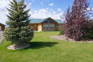A lodge with a large front lawn, a wooden cabin, and a clear sky.