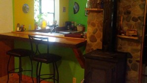 Une cuisine équipée d’un bar, d’une cuisinière et de deux tabourets de bar.