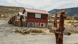 A rustic wooden building with a red roof and a signpost indicating distances to nearby locations. - Kims Cozy Rustic Cabin 5 min. from Cody (Cody)