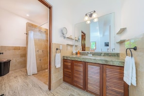 Une salle de bain équipée d’une douche, d’un lavabo, d’un miroir et d’un porte-serviettes.