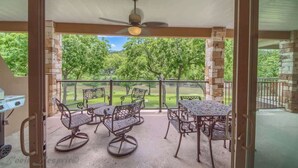 Un patio exterior con ventilador de techo, una parrilla y vistas a un paisaje verde.