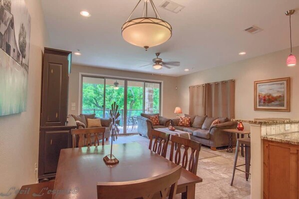 A spacious living area with a dining table, sofas, and a kitchen area.