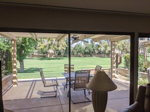 Un patio con mesa y sillas, una lámpara y vistas a un césped y árboles.