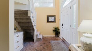 A staircase leading to a second floor, a framed picture on the wall, a potted plant, and a lamp on the right. - 47 Dune Lane - My Sunshine, Oceanfront 5 Bedroom, North Forest Beach (Hilton Head Island)