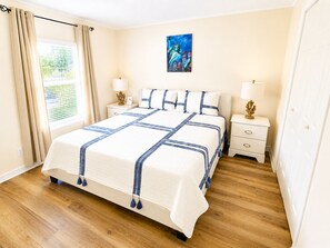 Ein Hotelzimmer mit einem großen Bett, zwei Nachttischen mit Lampen, einem Bild der Freiheitsstatue und einem Fenster mit Vorhängen.