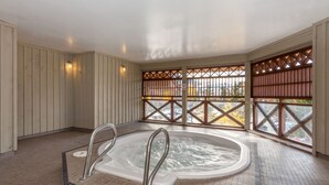 A spa area with a hot tub, wooden panel walls, and a view through a lattice window. - Mountain Views in Whistler Village (Whistler)