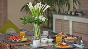 A breakfast table with plates of food, a vase of flowers, and a coffee pot. - Peaceful, Cozy Villa with Private Pool and Good Internet (Mia) (Pererenan)