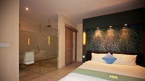 A hotel room with a glass-enclosed shower, a bed with white bedding and a patterned headboard, and a wall with a decorative light fixture. - Peaceful, Cozy Villa with Private Pool and Good Internet (Mia) (Pererenan)