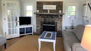 A living room with a stone fireplace, a television on a cabinet, a sofa, and a coffee table.