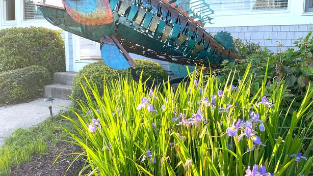 A house with a large fish sculpture in the garden.