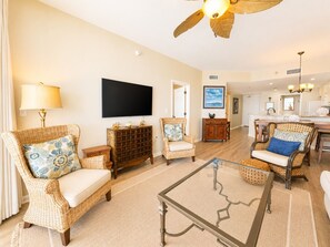 A living room with wicker furniture, a flat-screen TV, and a ceiling fan.