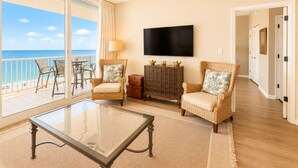 Habitación con balcón, televisión, muebles de mimbre y ventilador de techo.