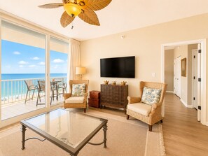 Ein Zimmer mit Balkon, Fernseher, Korbmöbeln und Deckenventilator.