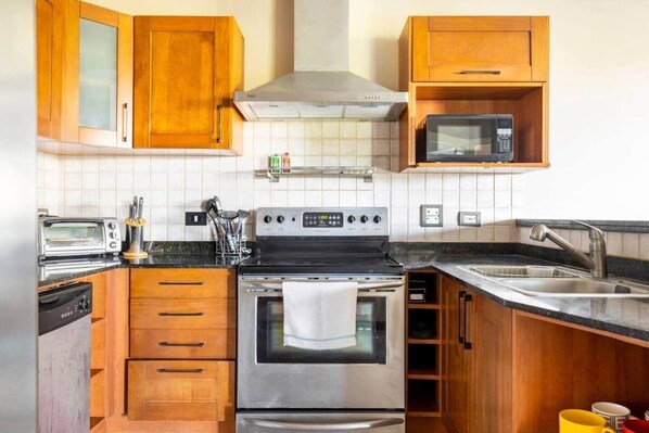 A kitchen with wooden cabinets, a microwave, a stove, and a sink.