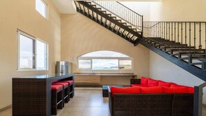 A spacious living area with a staircase, a dining table with chairs, and a red sofa. - Ocean view w/ pool, rooftop & beach (Playa Langosta)