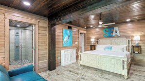 Un dormitorio tipo cabaña de madera con una cama, ducha y un cartel grande que dice 'SEA'.