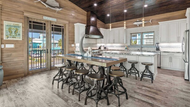 Una cocina con una isla grande, taburetes de bar y vistas a la playa.