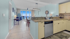 A modern kitchen with light blue walls, a granite countertop, and a dishwasher.