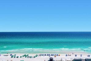 Ein Strand mit weißem Sand, klarem türkisblauem Wasser und einer Reihe von Sonnenschirmen.