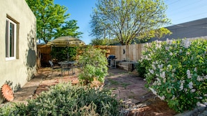 A patio with stone flooring, a table and chairs, and a striped umbrella.