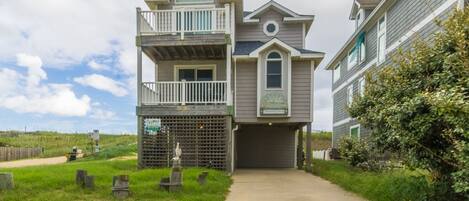 A two-story house with a balcony, a garage, and a pathway leading to the entrance.