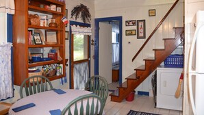 A kitchen with a wooden table, chairs, a bookshelf, and a washing machine.