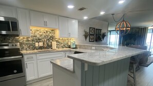 Una cucina moderna con mobili bianchi, un piano di lavoro in granito ed elettrodomestici in acciaio inossidabile.