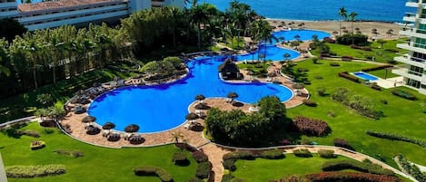 A resort with a large central pool, multiple smaller pools, and a beach area.