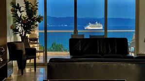 Una sala de estar moderna con un gran ventanal con vista a un cuerpo de agua y un crucero.