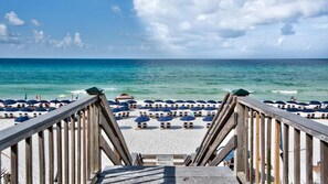 Een strand met een houten looppad naar de kust, strandparasols en een bordje dat afsluiting van het strand aangeeft vanwege hoogwater.