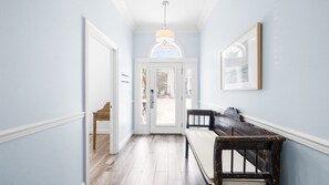 A hallway with a wooden bench, a door with a window, and a hanging light fixture.