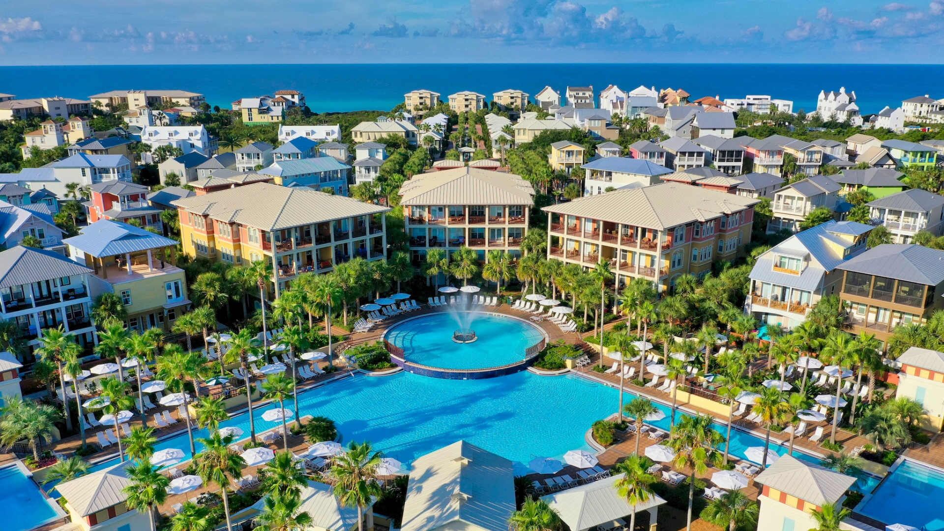 Un resort con piscina central, varias construcciones y vistas al océano.