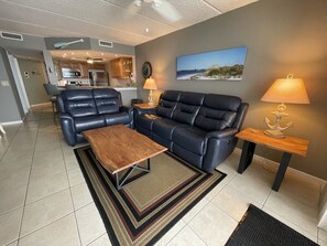 A living room with a leather sofa, a wooden coffee table, and a rug. There is a painting on the wall and a lamp on a side table.