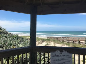 A wooden deck overlooking a beach with a sign acknowledging financial assistance for the development of the walkway.