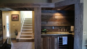 A wooden staircase leading to a second floor, a kitchen area with a countertop and cabinets, and a door with a framed picture.