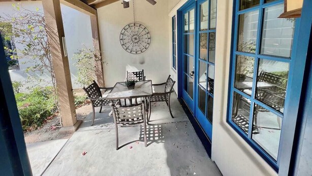 A covered patio with a table and chairs, a ceiling fan, and a wall clock. - Desert Tranquility 2 | 2BR Legacy Villa (La Quinta)