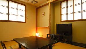 A traditional Japanese room with tatami flooring, a low table, chairs, a television, and a shoji screen. - Sadasuke (Kami)