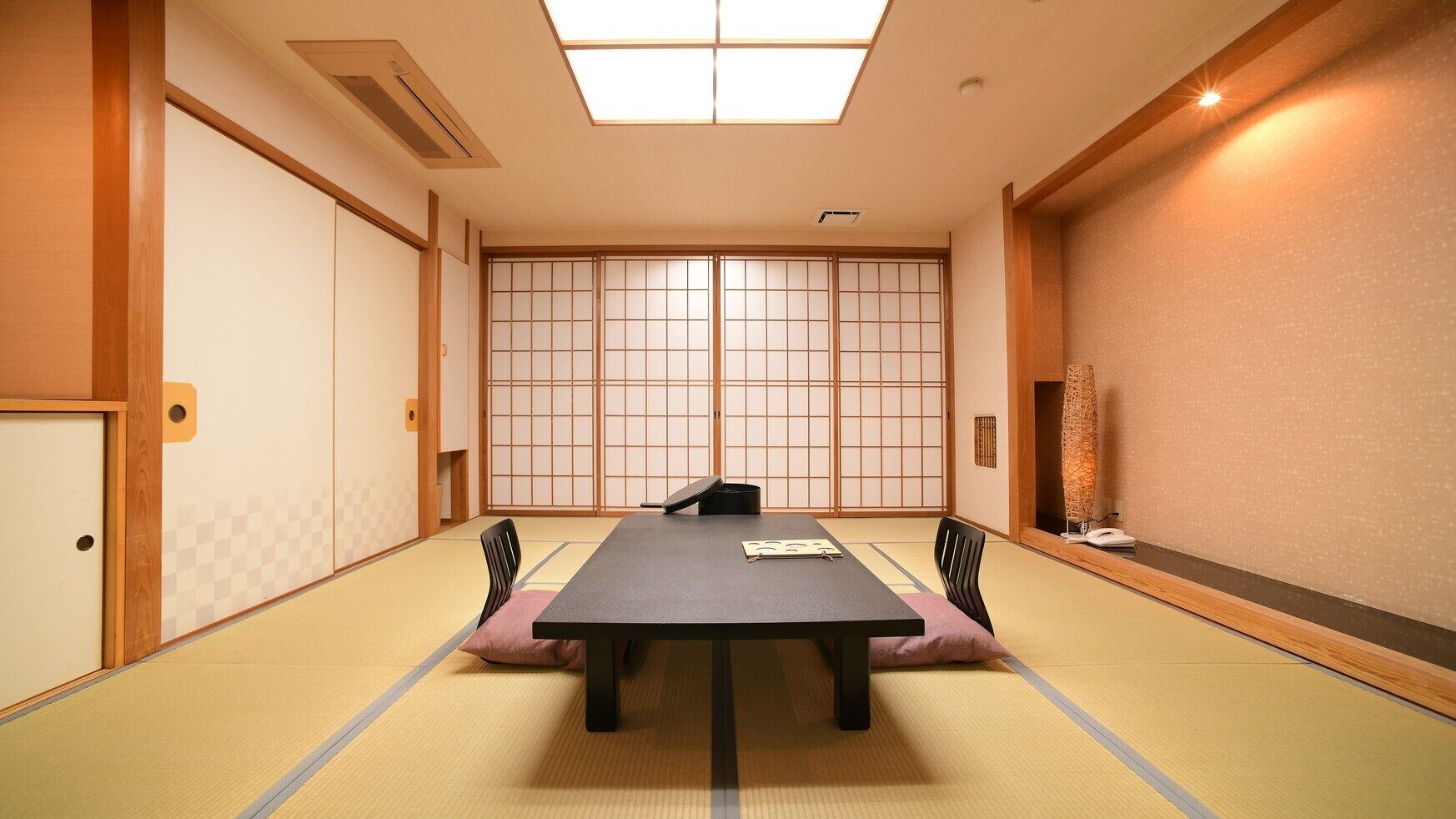 Ein traditioneller japanischer Raum mit Tatami-Bodenbelag, einem niedrigen Tisch und Shoji-Schirmwänden.