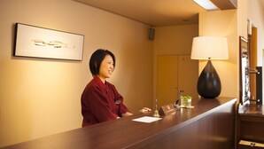 A reception desk with a framed artwork, a lamp, and a small plant. - Sadasuke (Kami)