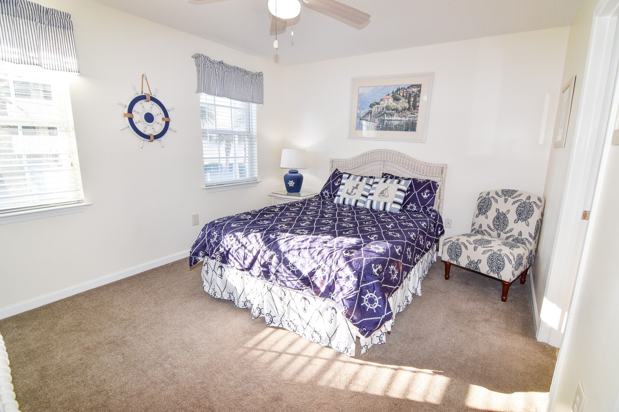 A bedroom with a bed, a chair, a wall clock, a lamp, and a framed picture.