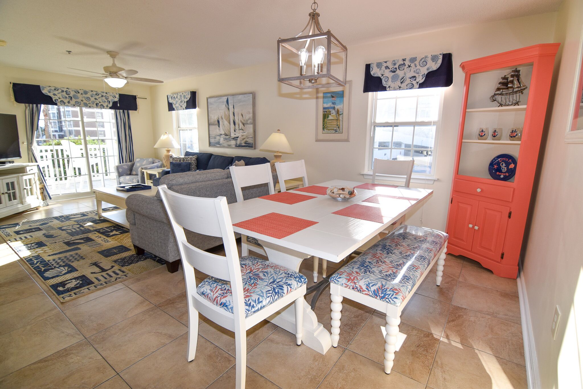 A dining area with a white table, red placemats, and patterned chairs.