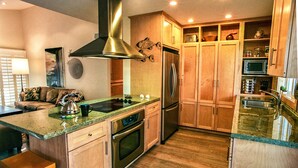 A modern kitchen with wooden cabinets, stainless steel appliances, and a granite countertop.